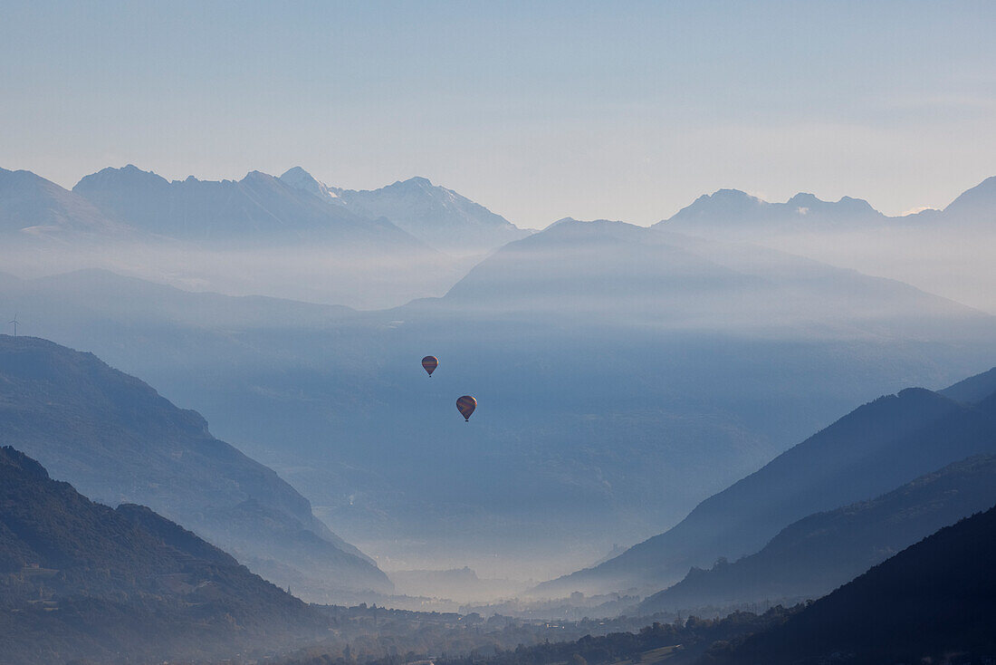 two hot air balloons fly over the city of Aosta, Aosta province, Valle d'Aosta district, Italy, Europe