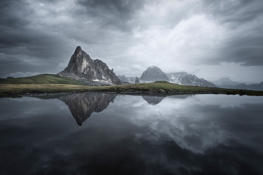 The Gusela mountain and the Tofana are reflected in the lake before the storm, Giau pass, Belluno, Italy.