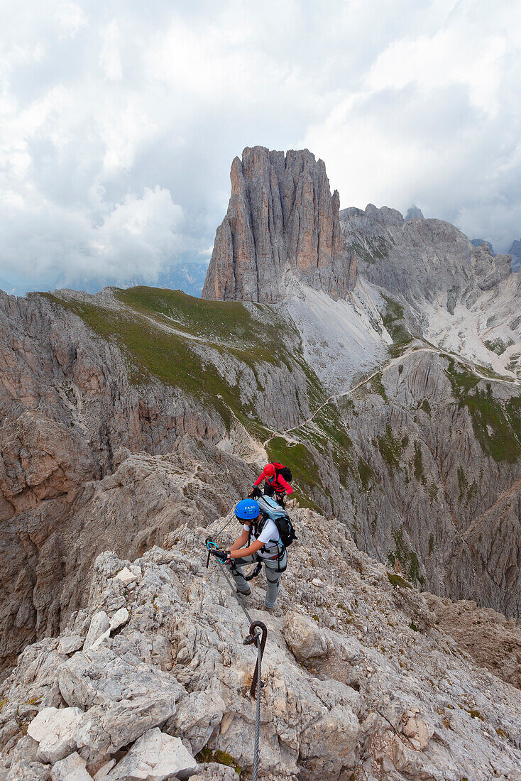 Two hikers along the Via Ferrata Roda di Vael, with Sforcella on the Background, Dolomites, Catinaccio Group, Fassa Valley, Trento province, Trentino-Alto Adige, Italy