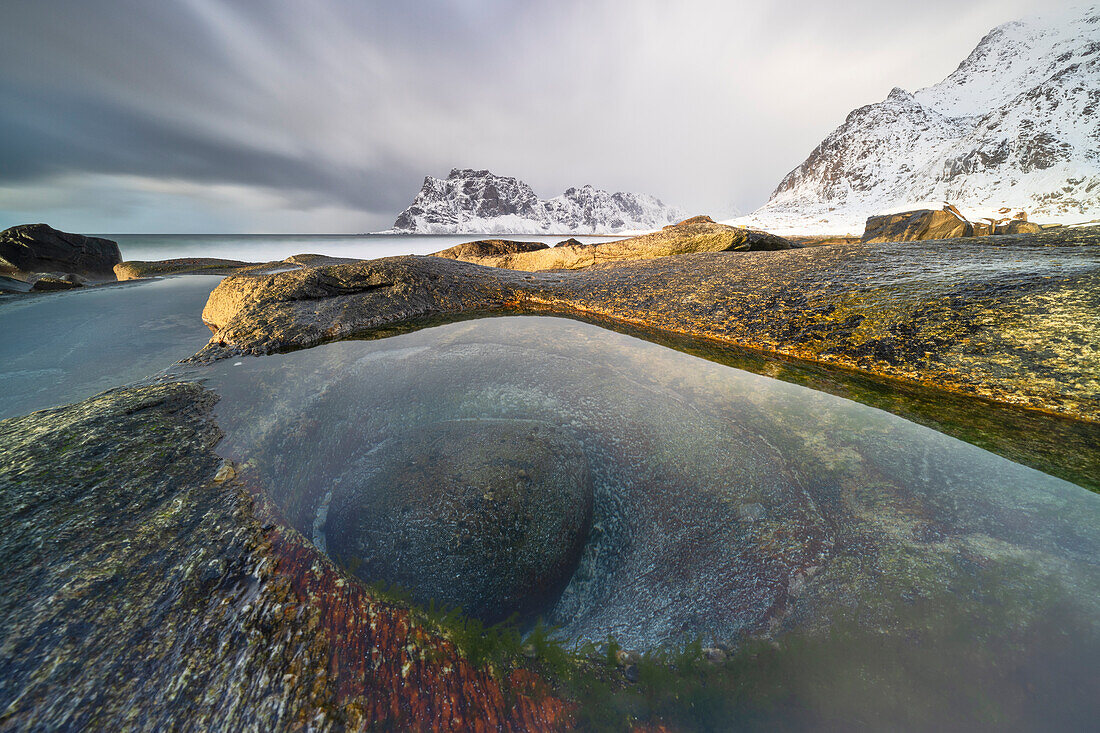 a long exposure to capture the sunset light at Uttakleiv beach during an winter day, with a famous eye of dragon in foreground, Vestvagoy, Lofoten island, Norway, Europe