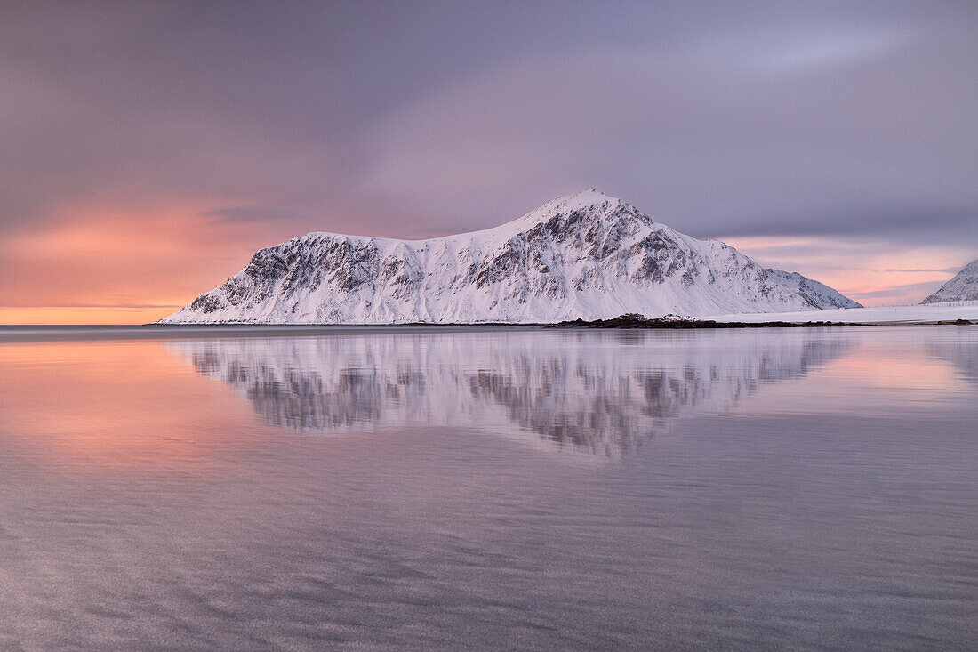 a warm light envelope the iconic mountainn in front at Skagsanden beach during a winter sunset, Ramberg, Lofoten island, Norway, Europe