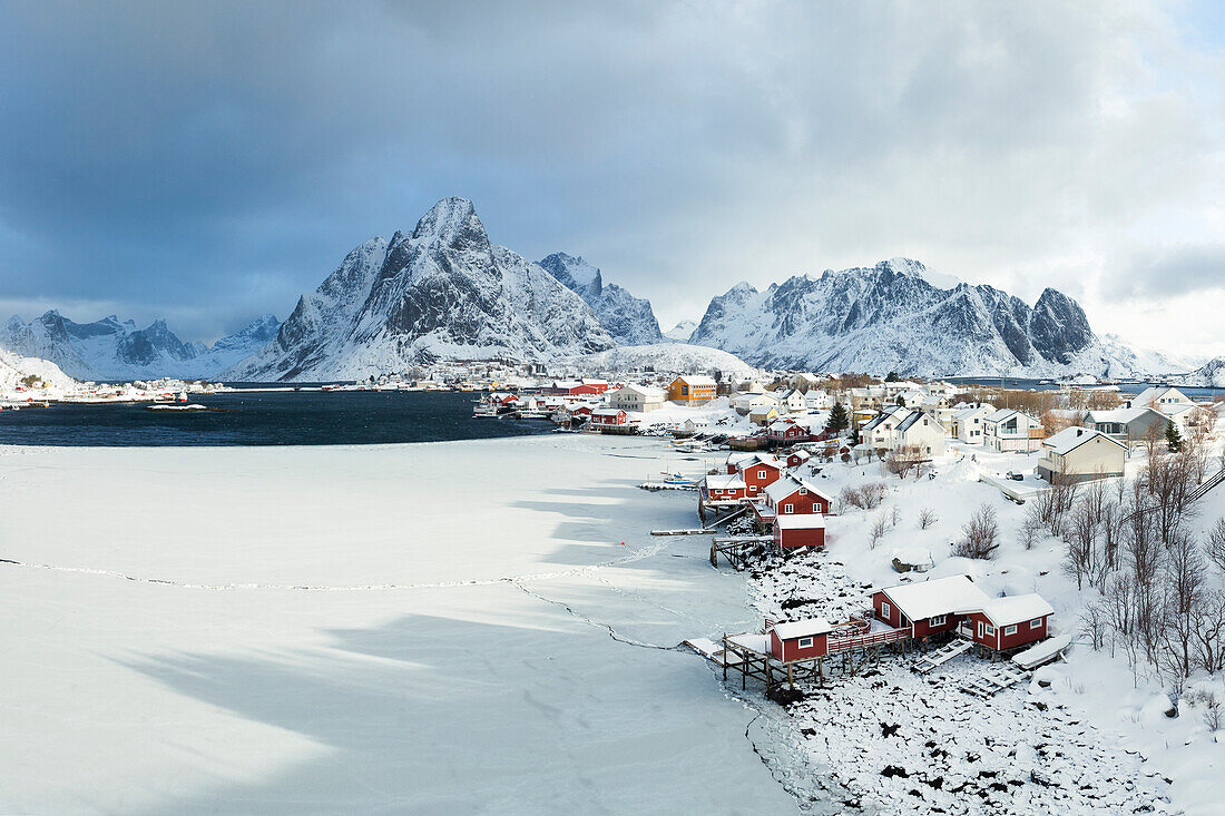 Wintertag im Dorf Reine mit schneebedecktem Berggipfel, Lofoten, Norwegen, Europa