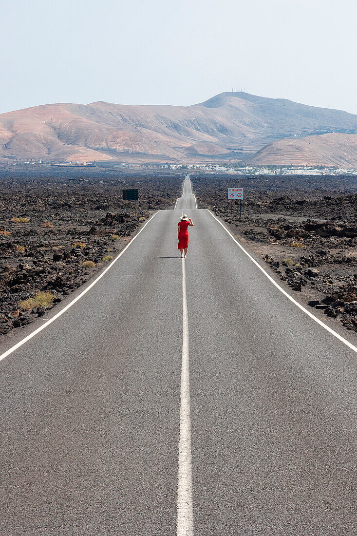 one tourist enjoys the beautiful view walking on the road field near to lava field, Lanzarote, Canary Island, Spain, Europe