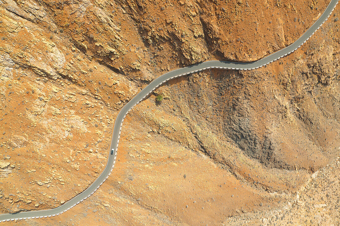 Vertikale Luftaufnahme einer Drohne von einem Auto, das die Straße zum Berg Fuerteventura entlang fährt, Fuerteventura, Kanarische Insel, Spanien, Europa