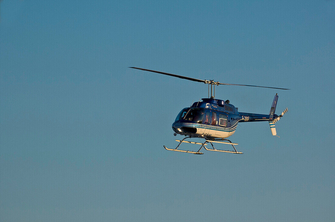 Hubschrauber schwebt in blauem Himmel.