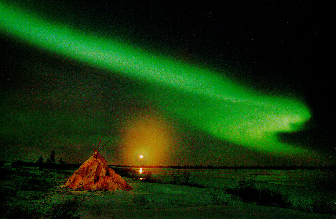 Aurora Borealis Northern Lights full moon over wigwam caribou skin tepee near Churchill, Manitoba, sub-arctic, Hudson Bay, Northern Canada