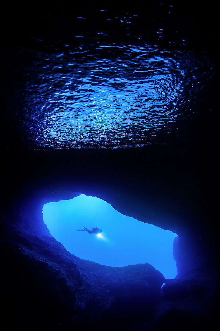 A diver passing by the entrance of the Zaffiro grotto, Italy
