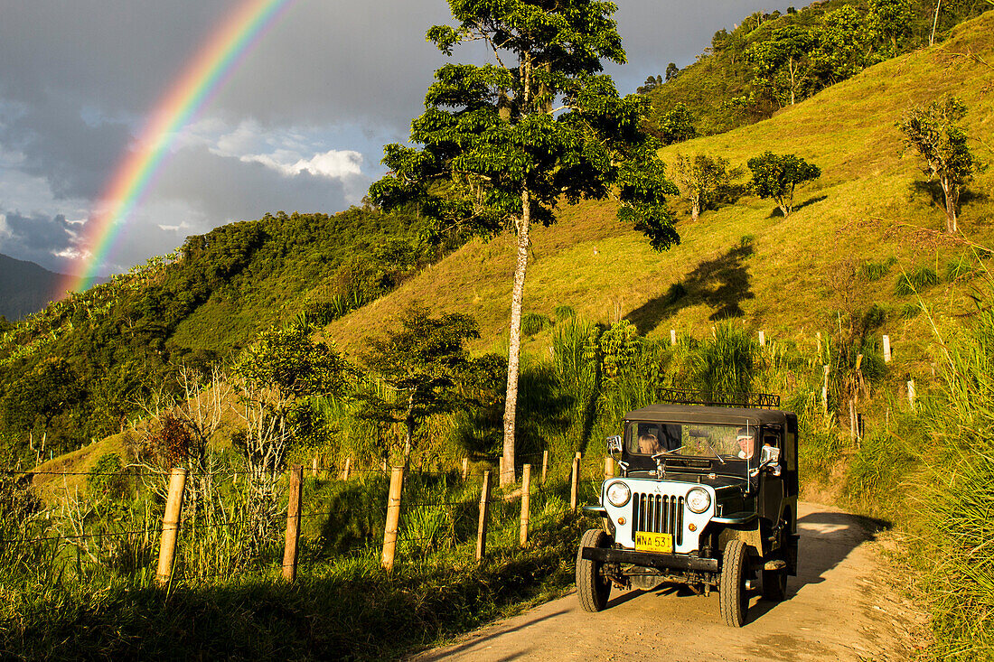 Landscape, jeep and rainbow near coffee plantaions