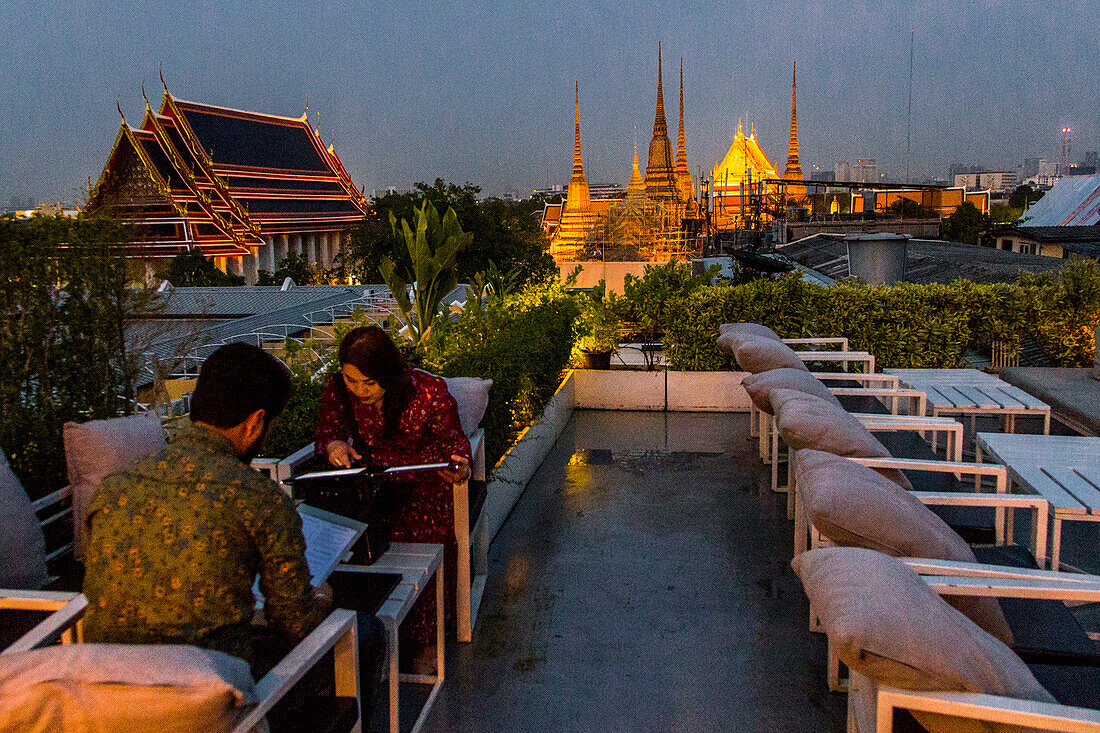 A couple before dinner in Bangkok during sunset with buddhist temples behind them