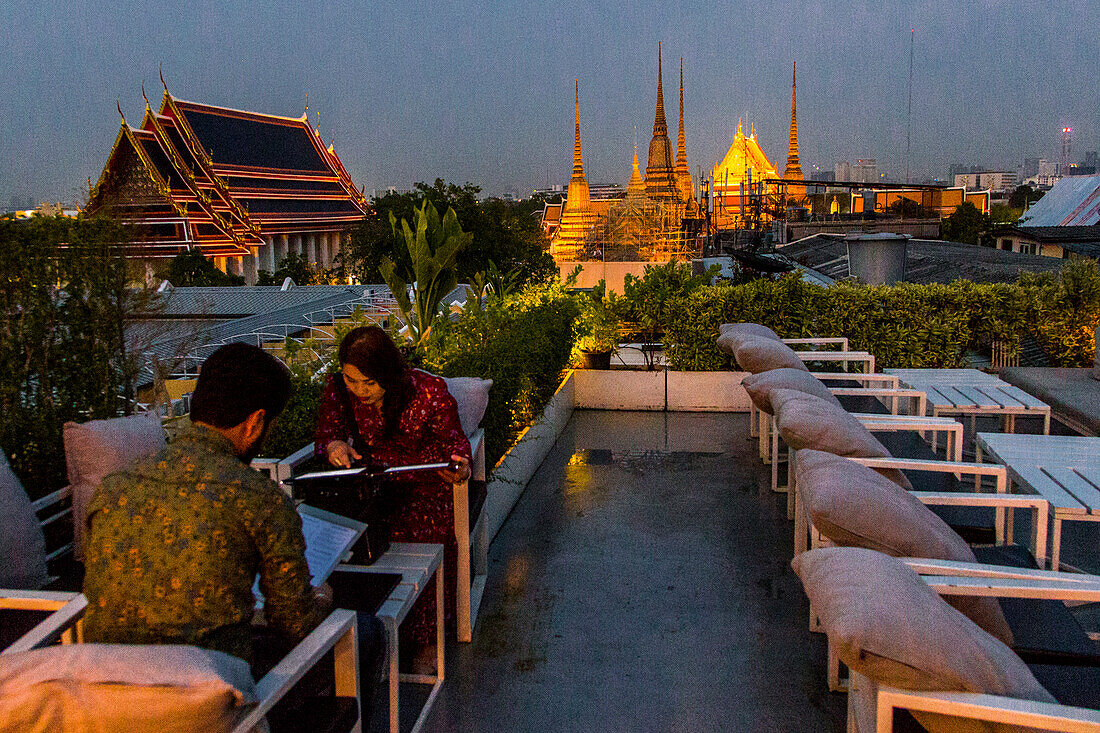 Ein Paar vor dem Abendessen in Bangkok bei Sonnenuntergang mit buddhistischen Tempeln im Hintergrund