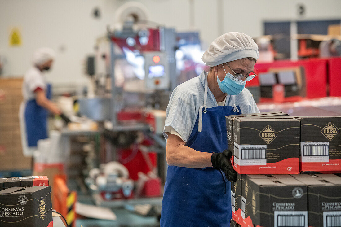 Frau arbeitet an der Verpackungslinie, Fischkonservenfabrik (USISA), Isla Cristina, Spanien
