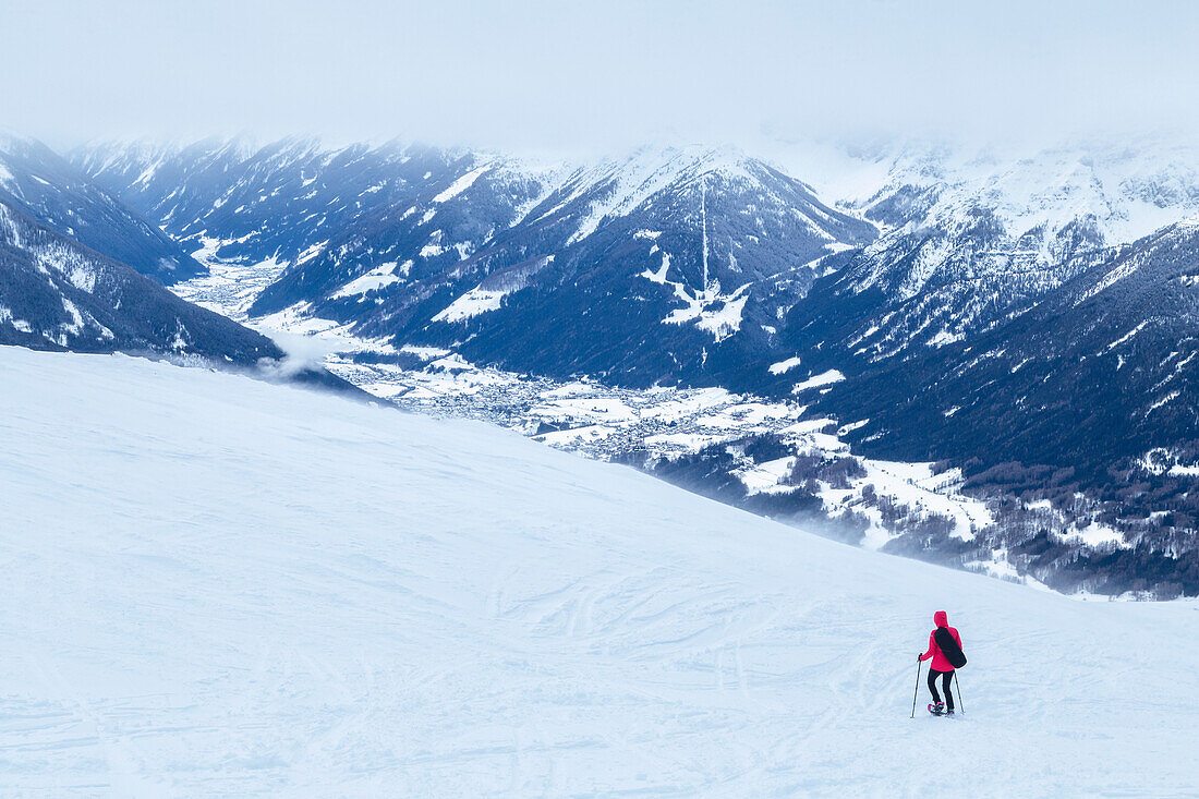 Ein Bergsteiger beim Schneeschuhwandern auf dem schneebedeckten Patscherkofel, mit dem Stubaital im Hintergrund, Tuxer Alpen, Innsbruck Land, Tirol, Österreich, Europa