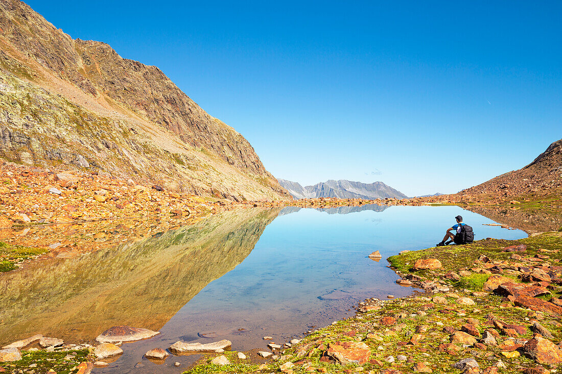 A mountaineer takes a break by Lake Freiger in the Stubai Alps, Langental Valley, Neustift im Stubaital, Innsbruck Land, Tyrol, Austria, Europe