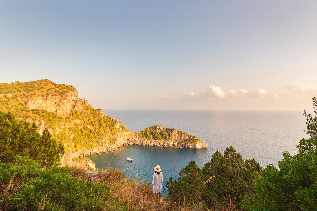 A woman admiring Monte di Luna and its bay at sunset, Sentiero degli Infreschi, Marina di Camerota, Salerno province, Campania region, Italy, Europe