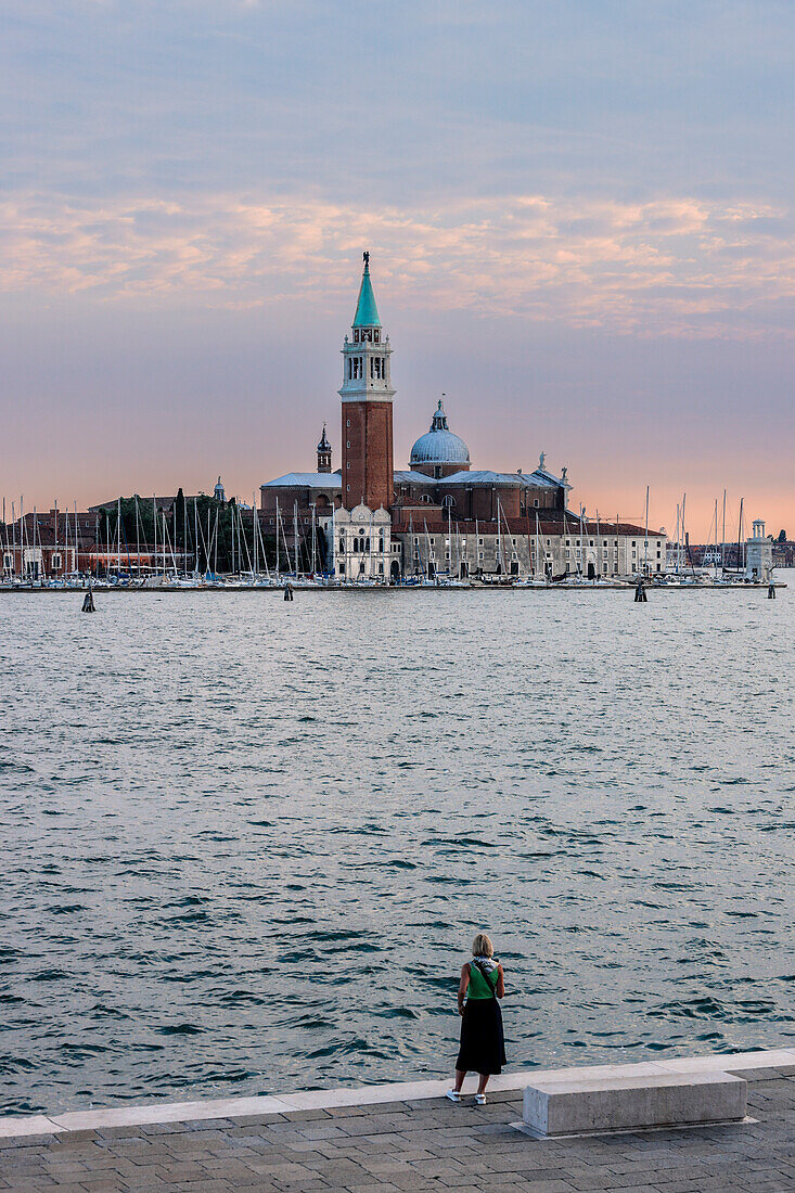 Italy, Veneto, Venice, a woman admires the Basilica of San Giorgio Maggiore at sunset