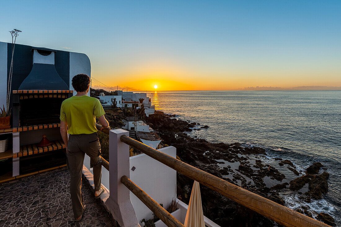 Spanien, Kanarische Inseln, Teneriffa, Boca Cangrejo, ein Mann bewundert den Sonnenaufgang über dem Meer (MR)