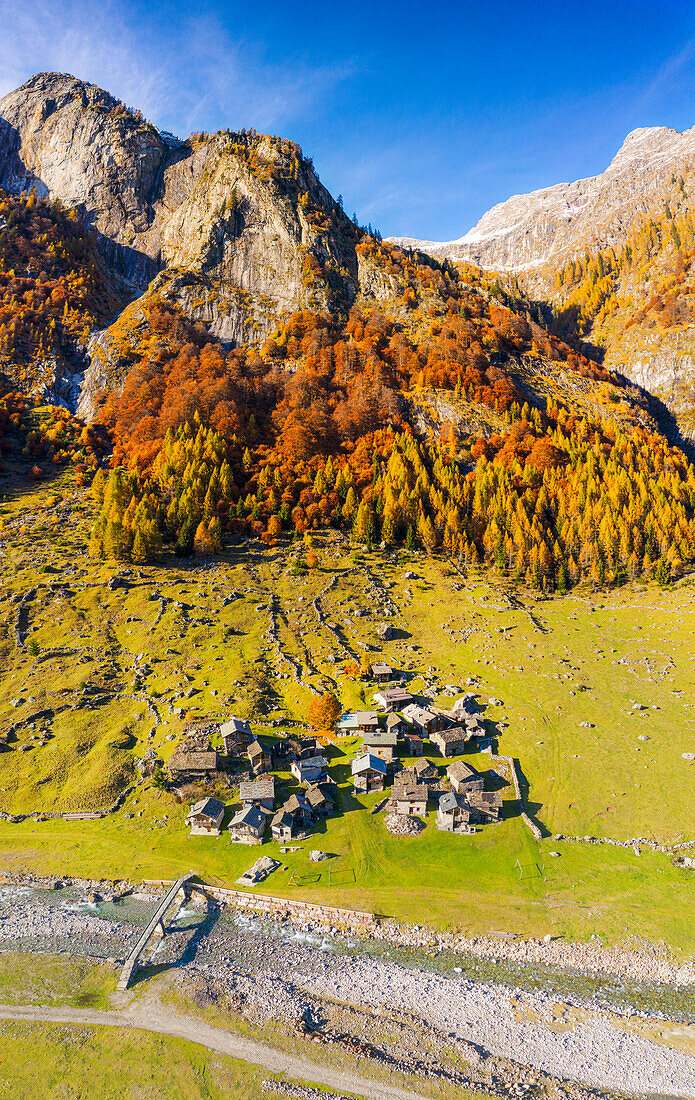 Alpiner Wildbach mit Blick auf das Alpendorf im Herbst. Val Bodengo, Valchiavenna, Valtellina, Lombardei, Italien, Europa.