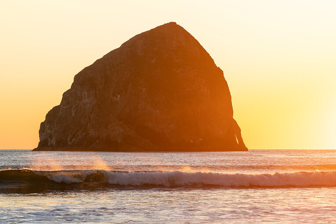 Haystack Rock and waves at Cape Kiwanda at sunset. Pacific City, Tillamook county, Oregon, USA.