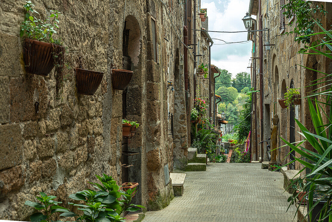 Characteristic alley, closed between tall tuff houses, overlooking the valley of the ancient village of Pitigliano. Pitigliano, Grosseto Province, Tuscany, Italy, Europe