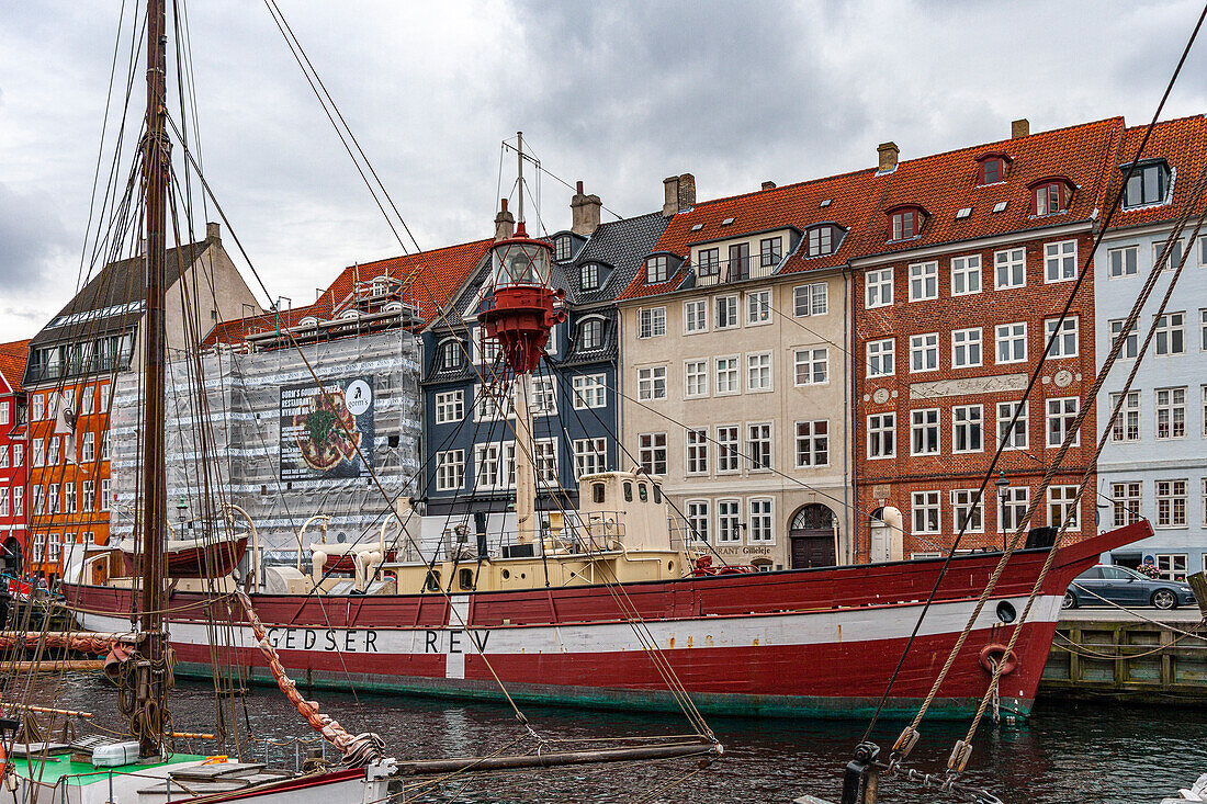 Rotes und weißes Schiff vor Anker in einem Kopenhagener Kanal. Im Hintergrund die charakteristischen, bunten dänischen Häuser. Kopenhagen, Dänemark, Europa