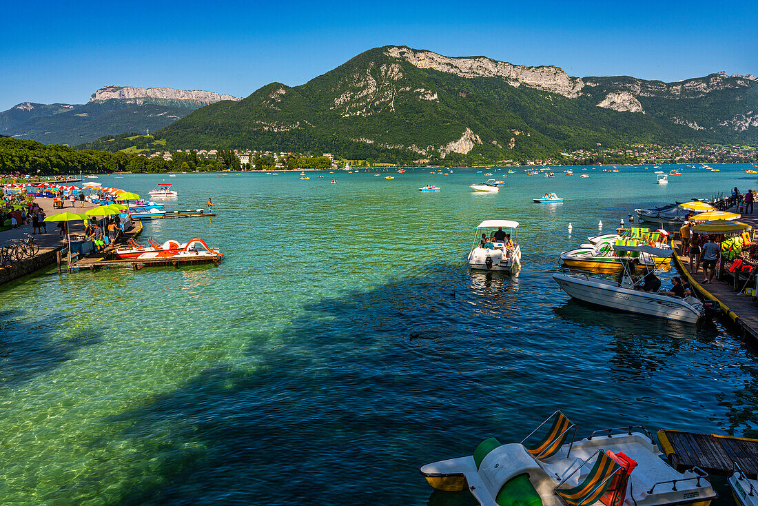 Sommerliches Vergnügen an einem Sommertag auf dem See von Annecy. Touristen auf Tretbooten und unter Regenschirmen. Annecy, Departement Savoyen, Region Auvergne-Rhône-Alpes, Frankreich