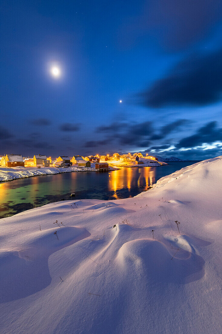 Das Küstendorf Sorvaer ist während der Dämmerung im kalten arktischen Winter mit Schnee bedeckt (Insel Soroya, Hasvik, Troms og Finnmark, Norwegen)