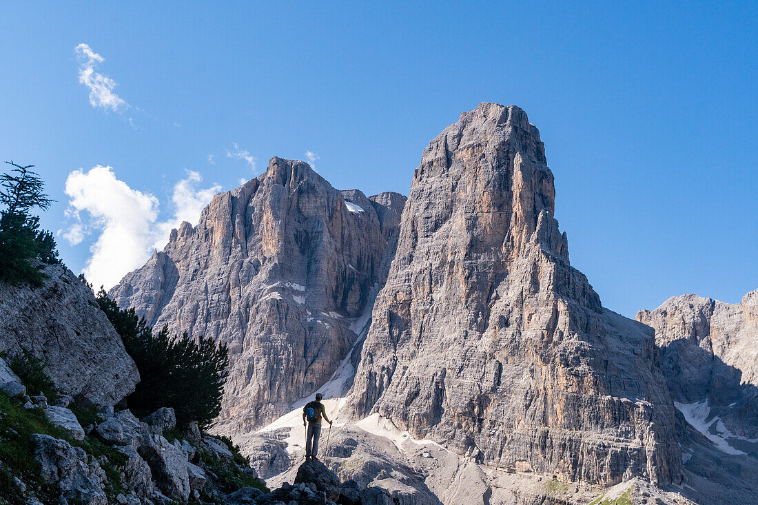 A hiker in silhouette admiring the Tosa peak along the pathway to Rifugio Pedrotti from Madonna di Campiglio, Trentino, Italy.