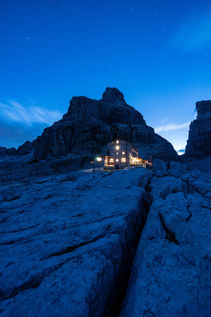 Die Lichter der Pedrotti-Hütte während der blauen Stunde an einem Sommertag. Molveno, Trentino, Italien.