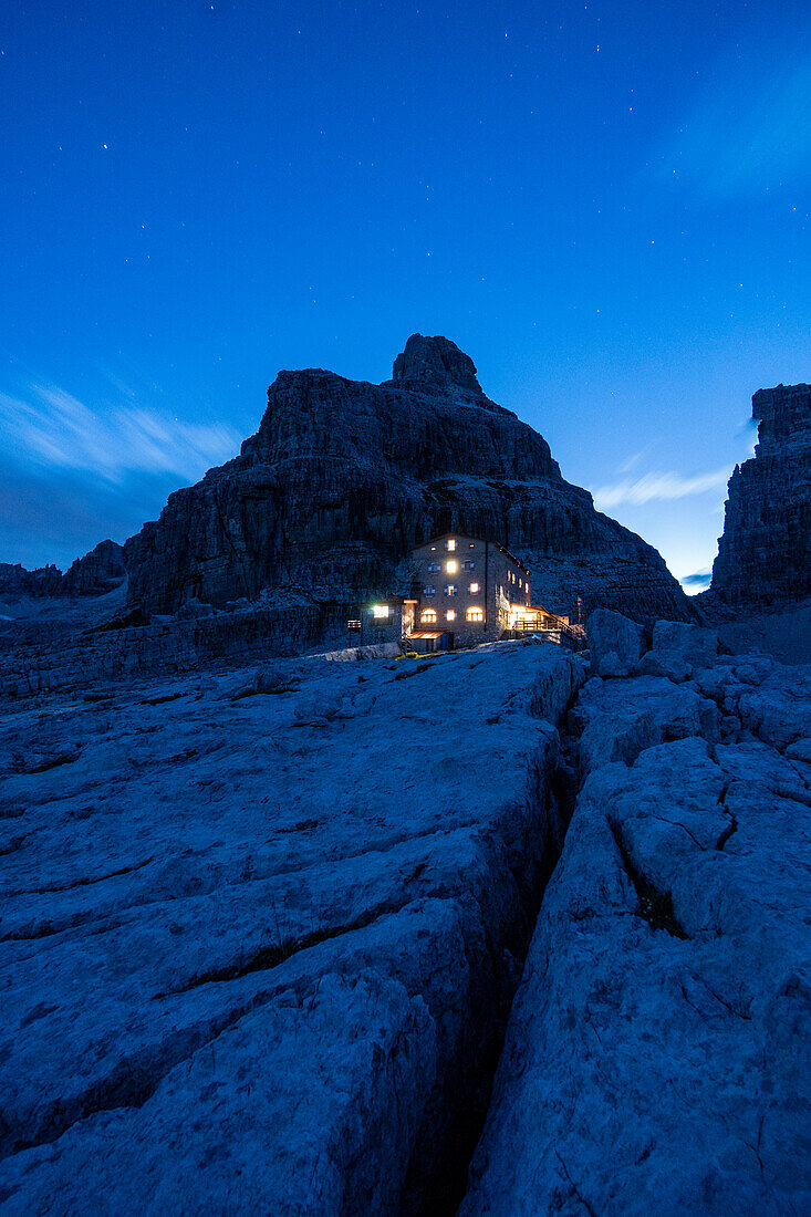 The lights of Pedrotti refuge during blue hour in a summer day. Molveno, Trentino, Italy.