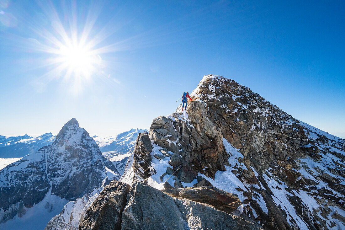 Alpinist on the final ridge to the summit of Dent d Herens peak. With the north face of Matterhorn in the background. Valpelline valley, Bionaz, Aosta Valley, Alps, Italy, Europe.