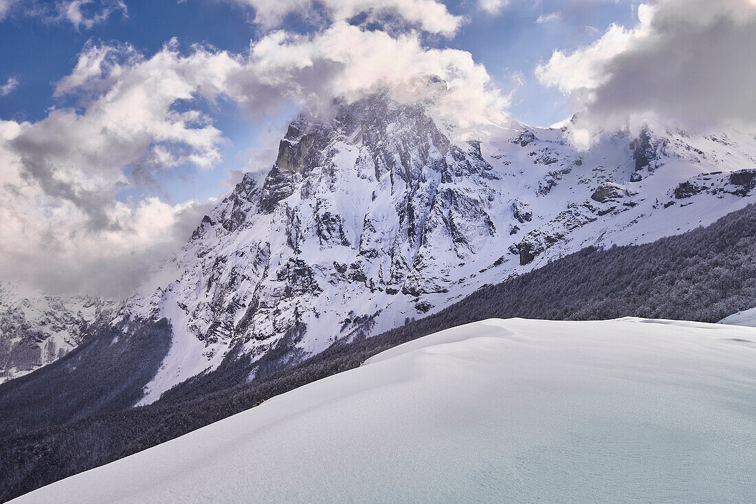 Der schneebedeckte Berg Corno Grande kämpft gegen die Wolken an einem kalten Winternachmittag. Pietracamela, Bezirk Teramo, Abruzzen, Italien