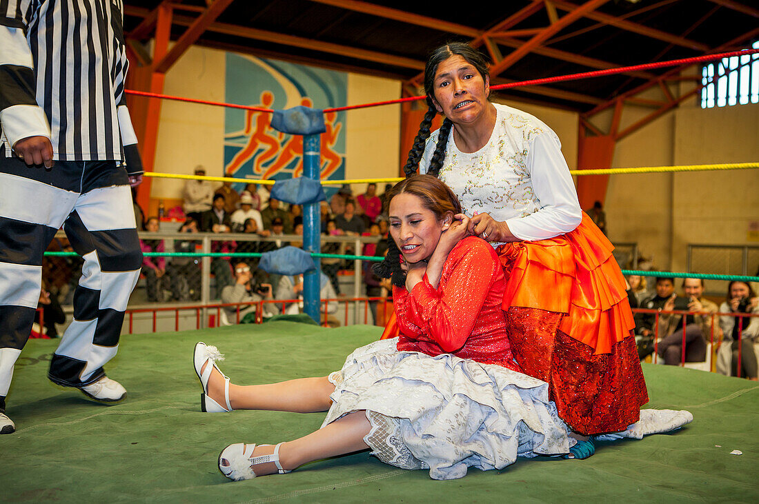 Lucha Libre. Kampf zwischen Dina mit orangefarbenem Rock und Benita la Intocable, Cholitas Wrestlerinnen, mit Schiedsrichter, Sportzentrum La Ceja, El Alto, La Paz, Bolivien