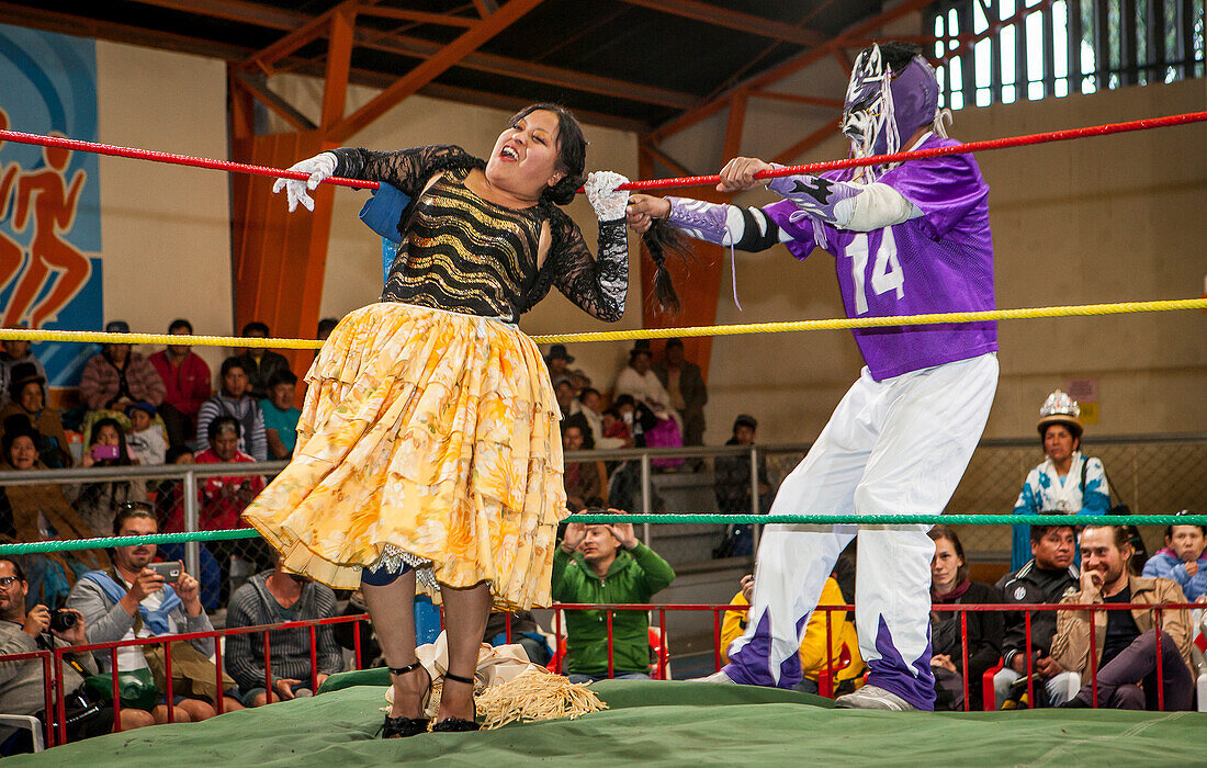 Lucha Libre. Männlicher Kämpfer dehnt das Haar von cholita Julieta, Ringer im Kampf, Sportzentrum La Ceja, El Alto, La Paz, Bolivien