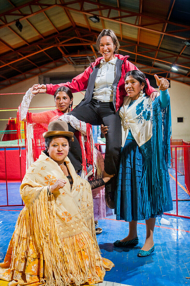 Lucha Libre. Nach der Show. Ein Zuschauer lässt sich mit den Cholitas-Kämpferinnen fotografieren. Unten Julieta, Celia la Simpatica, und Dina mit blauem Kleid, Cholitas Wrestlerinnen, Sportzentrum La Ceja, El Alto, La Paz, Bolivien