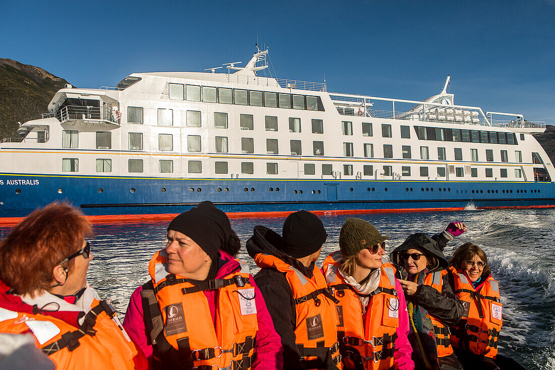 Passagiere des Ventus-Kreuzfahrtschiffs gehen mit dem Zodiac von Bord und erkunden die Ainsworth Bay, im Hintergrund das Ventus-Kreuzfahrtschiff, Tierra del Fuego, Patagonien, Chile