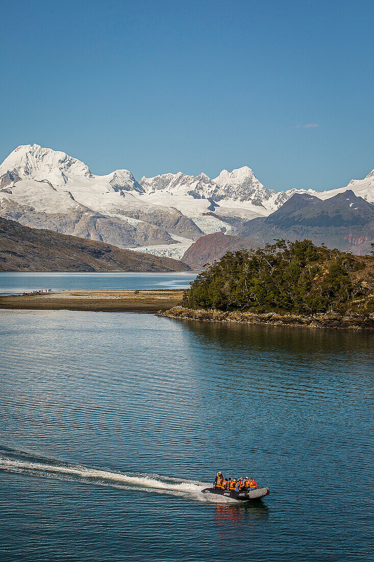 Cordillera Darwin and explorers riding a zodiac, in Ainsworth Bay, PN Alberto de Agostini, Tierra del Fuego, Patagonia, Chile