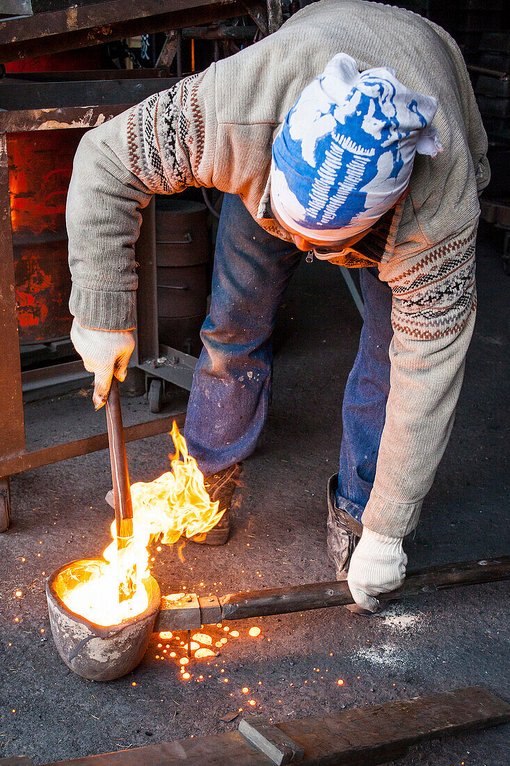 Warten auf die richtige Temperatur. Takahiro Koizumi trägt geschmolzenes Eisen mit einem Löffel, um es in die Form zu gießen, um eine eiserne Teekanne oder Tetsubin herzustellen, nanbu tekki, Werkstatt der Familie Koizumi, Handwerker seit 1659, Morioka, Präfektur Iwate, Japan