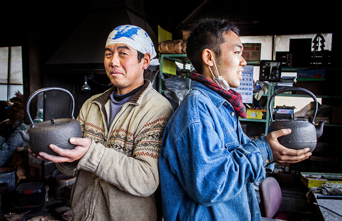 Takahiro Koizumi (links) und sein Assistent (rechts) zeigen ihre fertige Arbeit, eiserne Teekannen oder Tetsubin, nanbu tekki, Werkstatt der Familie Koizumi, Handwerker seit 1659, Morioka, Präfektur Iwate, Japan