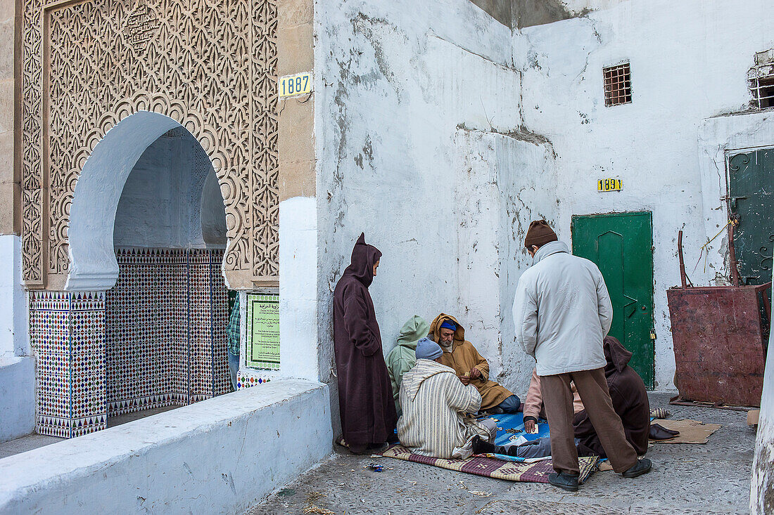 Men playing cards, and facade of Al Harraquia Zaouia, medina, Tetouan, UNESCO World Heritage Site, Morocco