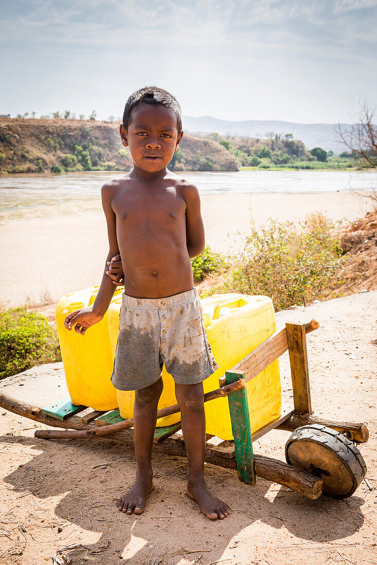 Kind arbeitet bei der Verteilung von Wasser in Containern, Morondava, Madagaskar