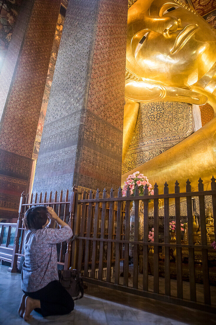 Betende Frau, goldener großer Buddha, im Wat Pho oder Wat Phra Nakhon Tempel in Bangkok, Thailand