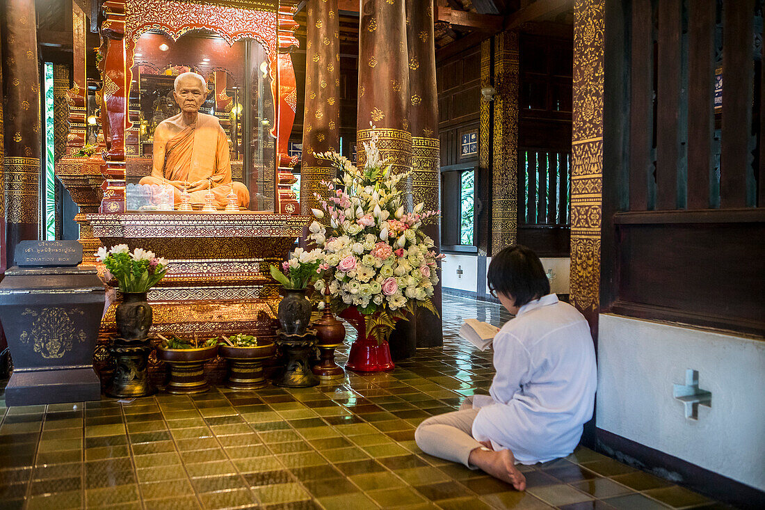 Believer praying, monk statue, in Wat Chedi Luang temple, Chiang Mai, Thailand