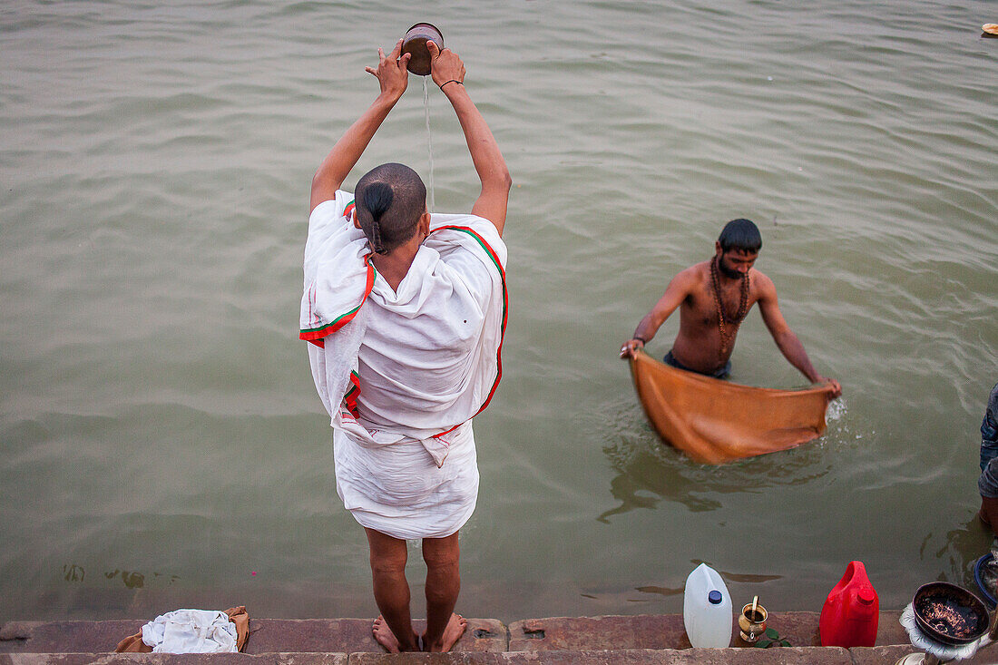 Ein Mann betet und badet an den Ghats des Ganges, Varanasi, Uttar Pradesh, Indien.