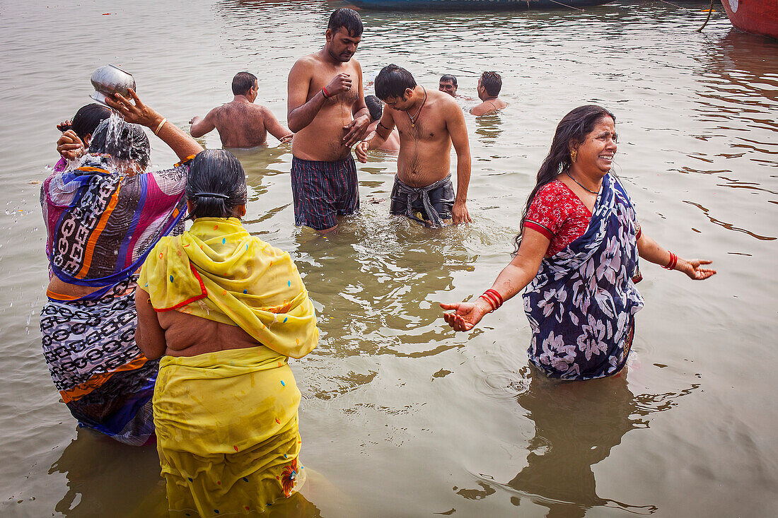 Frauen und Männer, die beten und baden, an den Ghats des Ganges, Varanasi, Uttar Pradesh, Indien.