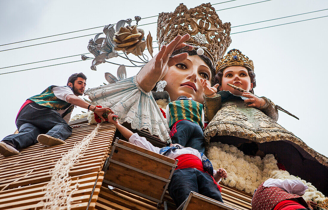 Männer legen Blumenopfer auf die große hölzerne Statue der Virgen de los Desamparados, Fallas-Fest, Plaza de la Virgen, Valencia