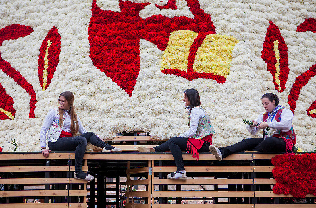 Frauen legen Blumenopfer auf die große hölzerne Statue der Virgen de los Desamparados, Fallas-Fest, Plaza de la Virgen, Valencia