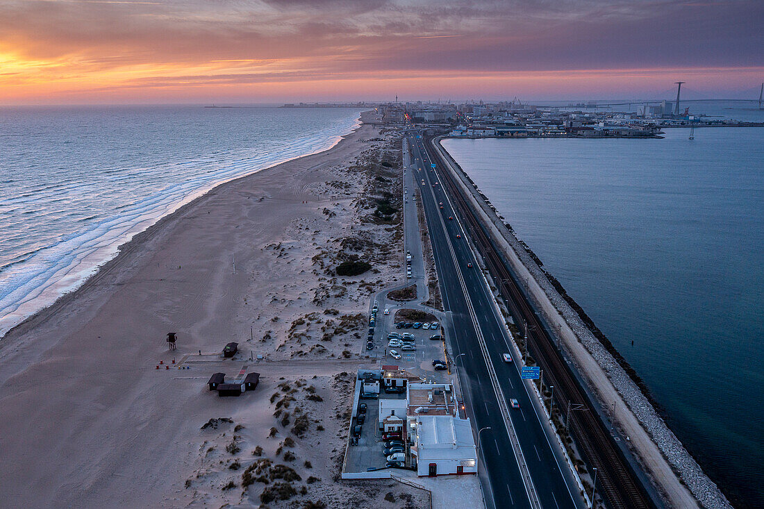 Cádiz im Hintergrund. Luftaufnahme des Strandes und der Straße CA-33, auch AV Vía Augusta Julia genannt, von San Fernando nach Cadiz, Provinz Cadiz, Andalusien, Spanien