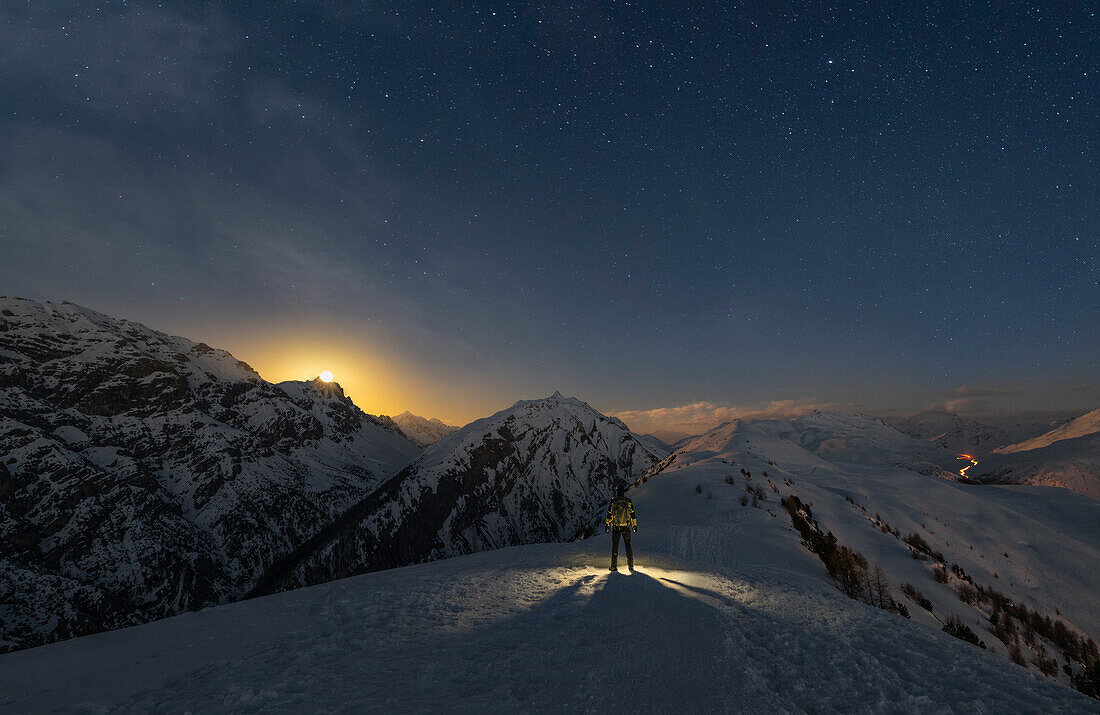 Ein Mann beobachtet den Mondaufgang am Crap del la Parè, Livigno, Sondrio, Valtellina, Lombardei, Italien, Südeuropa