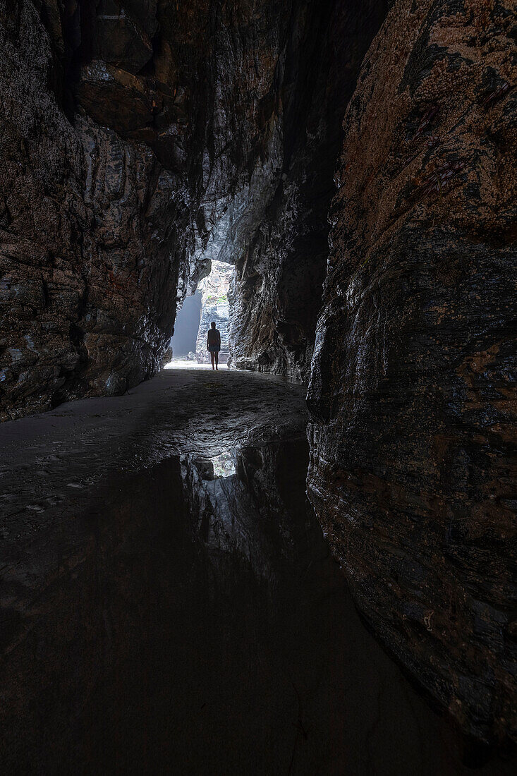 Eine Frau geht in einer Höhle am Playa de Las Catedrales, Ribadeo, Galicien, Spanien, Iberische Halbinsel, Westeuropa