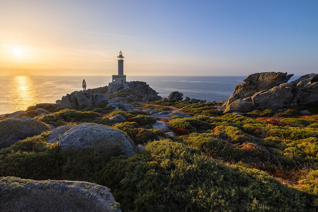 Eine Frau beobachtet den Leuchtturm von Punta Nariga bei Sonnenuntergang im Sommer, Costa da Morte, Galicien, Spanien, Iberische Halbinsel, Westeuropa